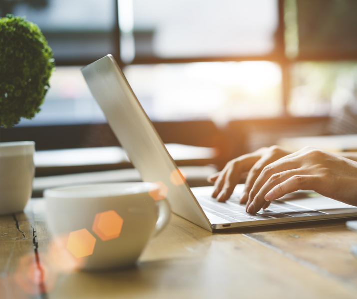 closeup-hands-of-woman-working-using-digital-laptop-computer-and-drinking-coffee