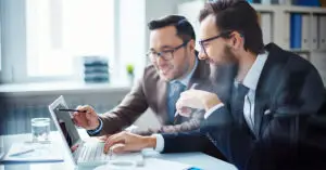 young-businessman-pointing-at-laptop-display-while-presenting-business-project-to-partner