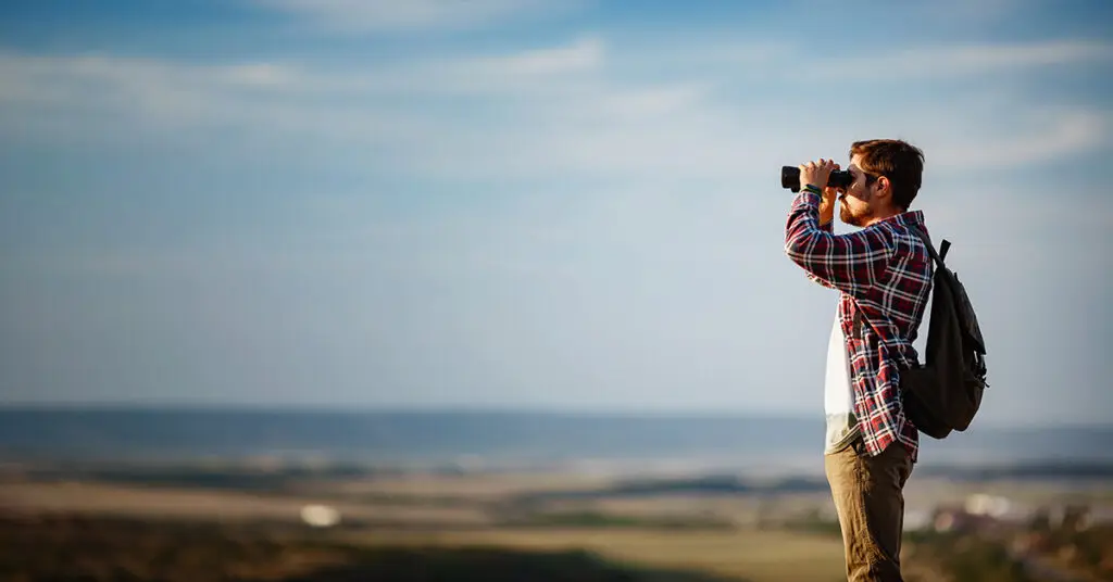 guy-looking-at-binoculars-on-hill