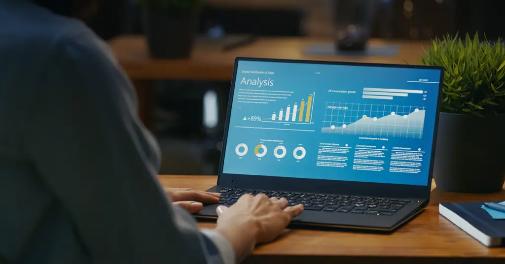 female-analyst-at-her-desk-works-on-a-laptop-showing-statistics-graphs-and-charts
